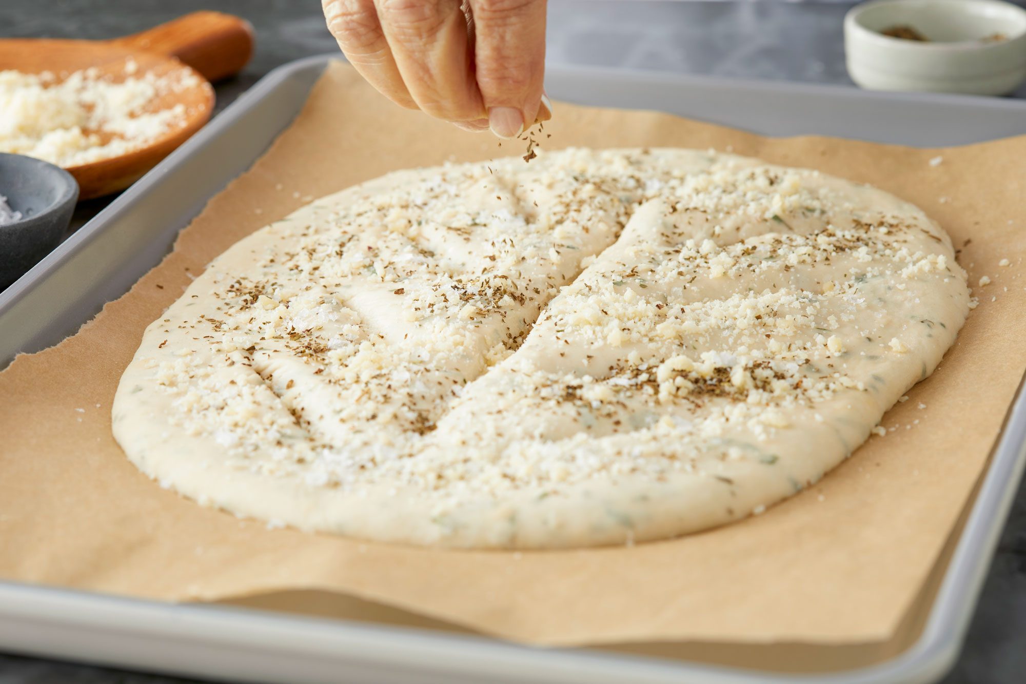 Sprinkling Dried Basil on a Fougasse Dough