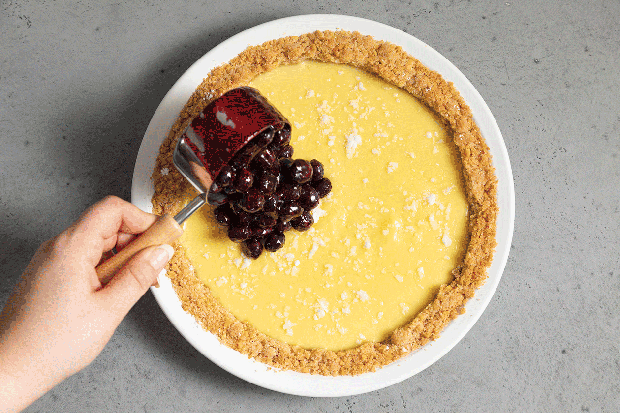Adding blueberry topping to custard topped pie
