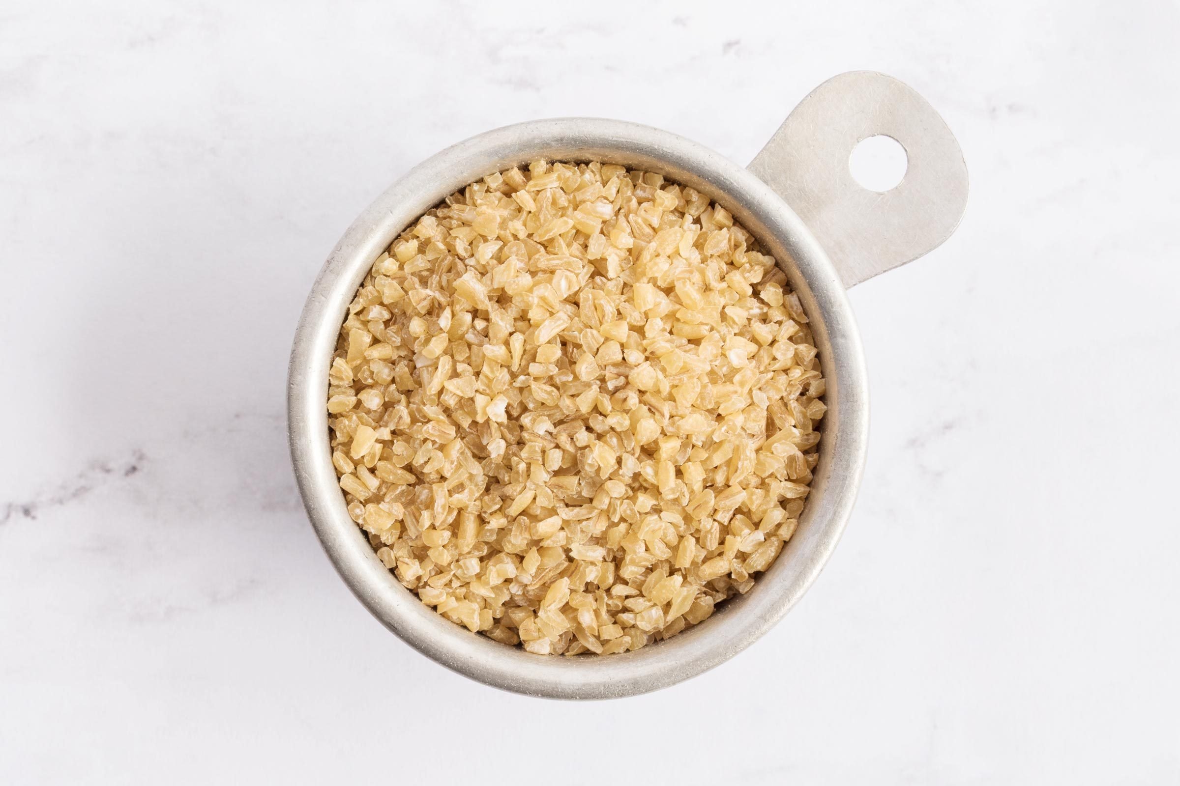 raw bulgar in a measuring cup on a marble counter