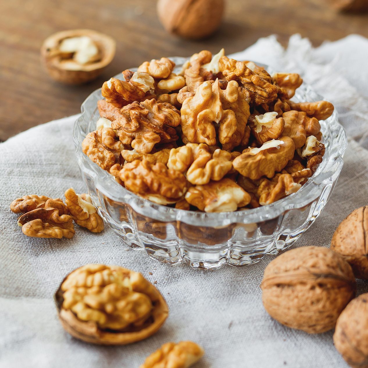 Glass bowl with walnuts on rustic homespun napkin. Healthy snack.