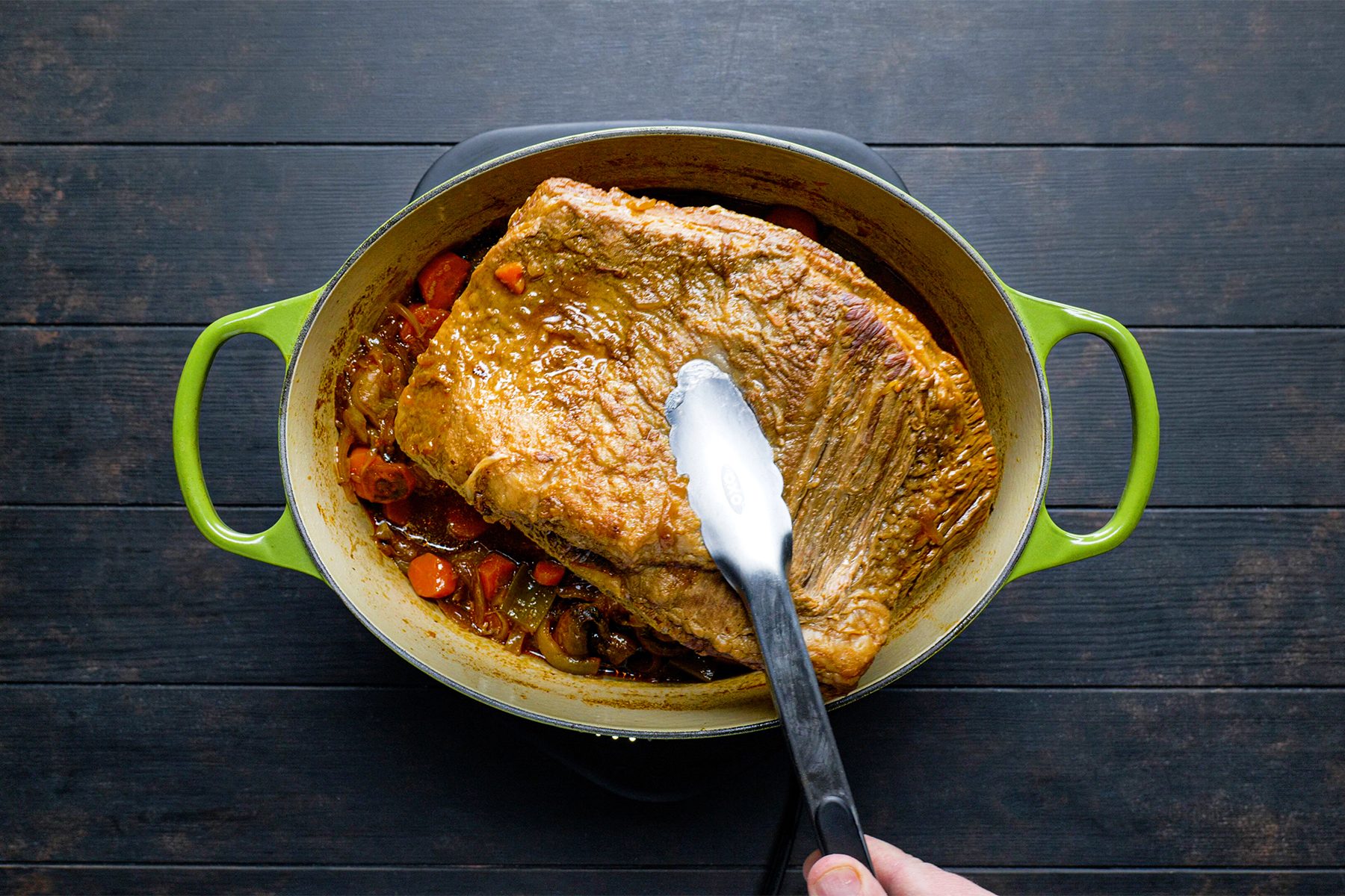 A person holding a spatula over a large piece of meat