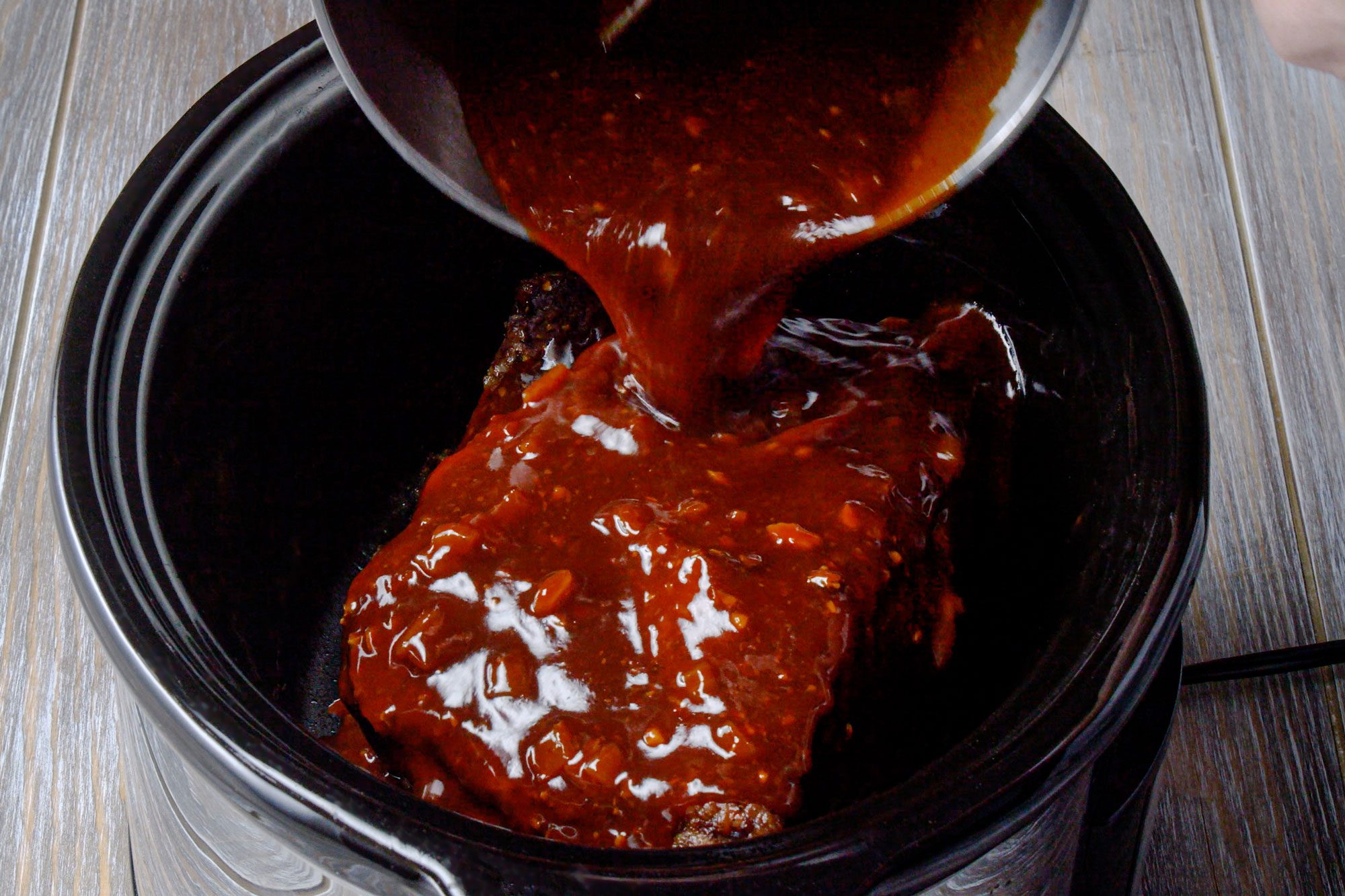 Return the brisket to the cooker and add barbecue sauce