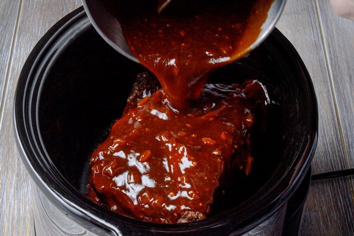 Return the brisket to the cooker and add barbecue sauce