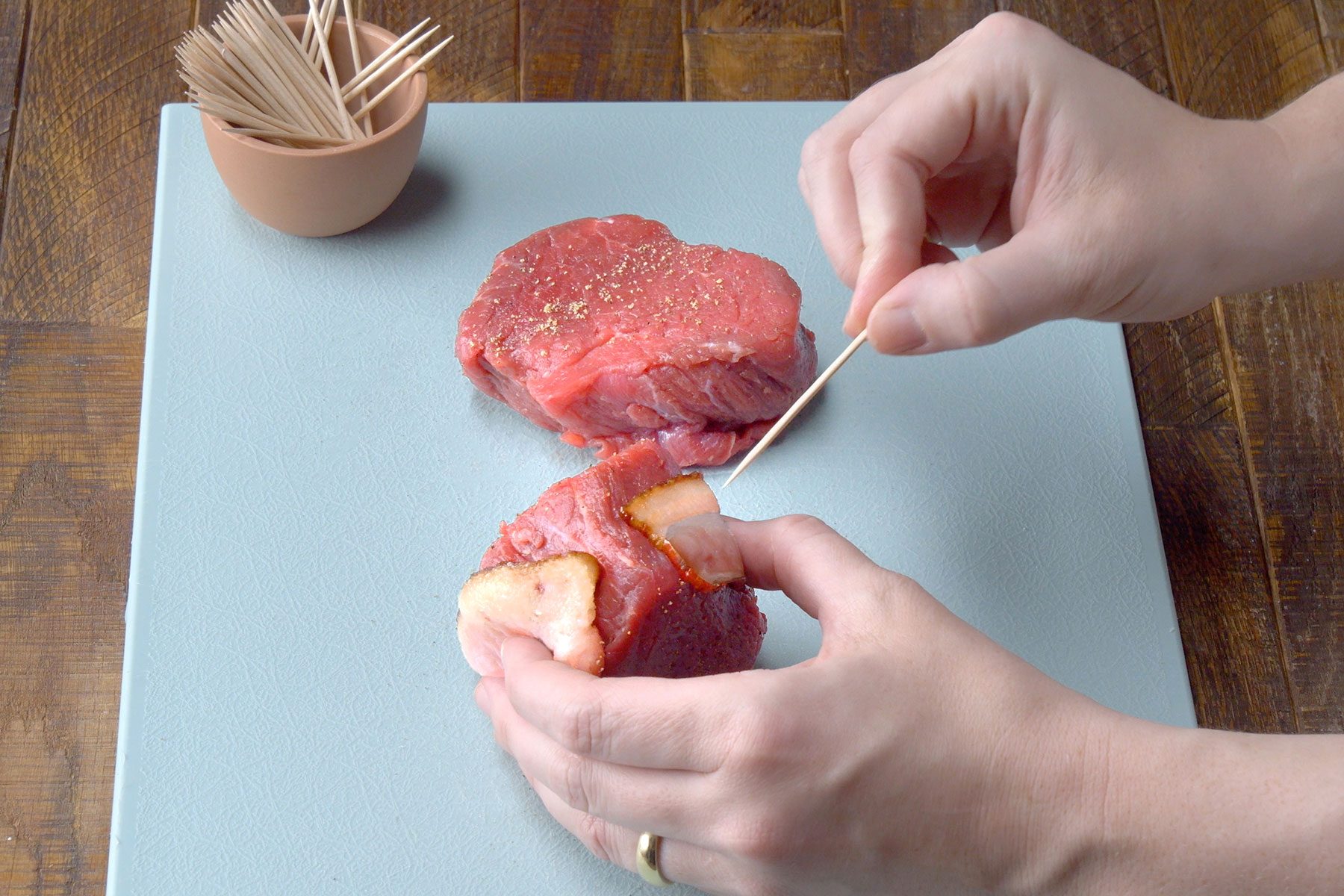 Wrapping the steaks with bacon strips