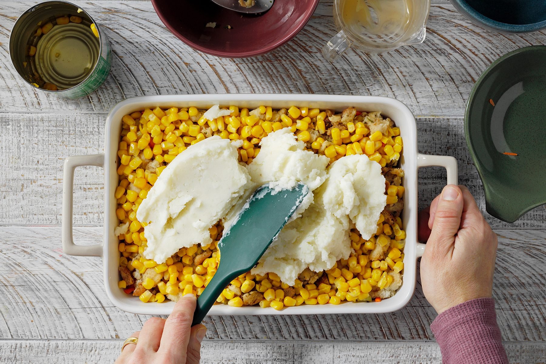 A person Spreading mashed potatoes with a spatula