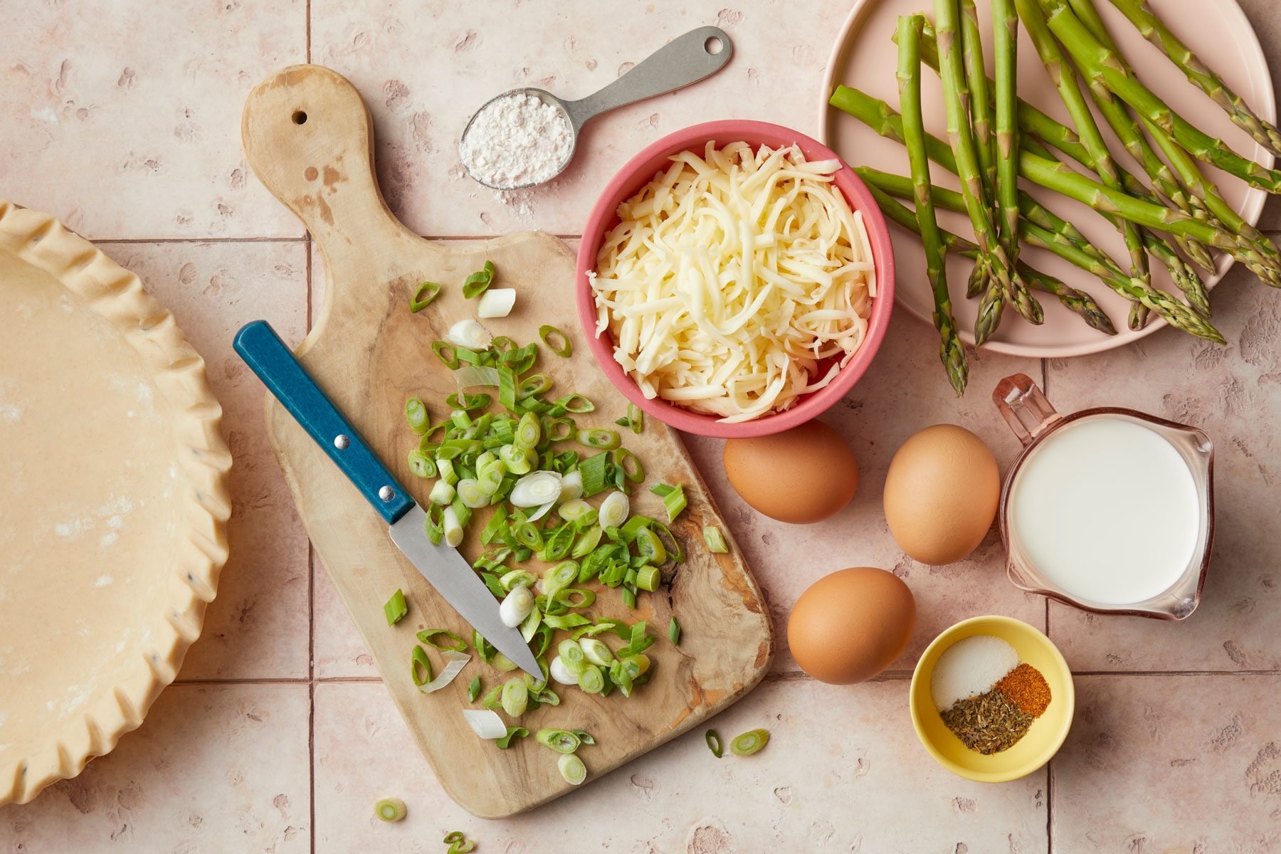 Pie dough eggs vegetables on countertop with a tray and a knife