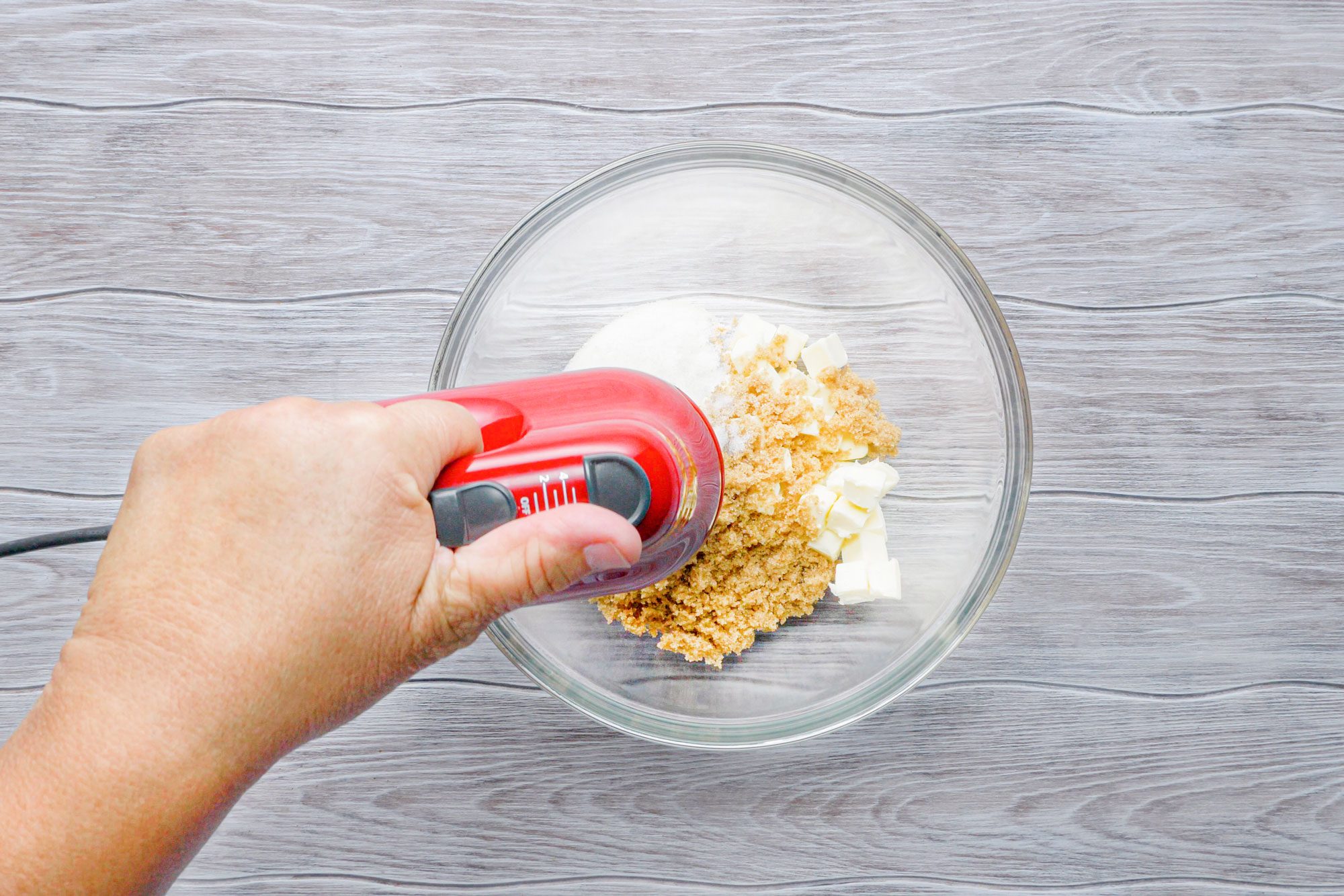 Mixing butter and sugar in a bowl with hand mixer