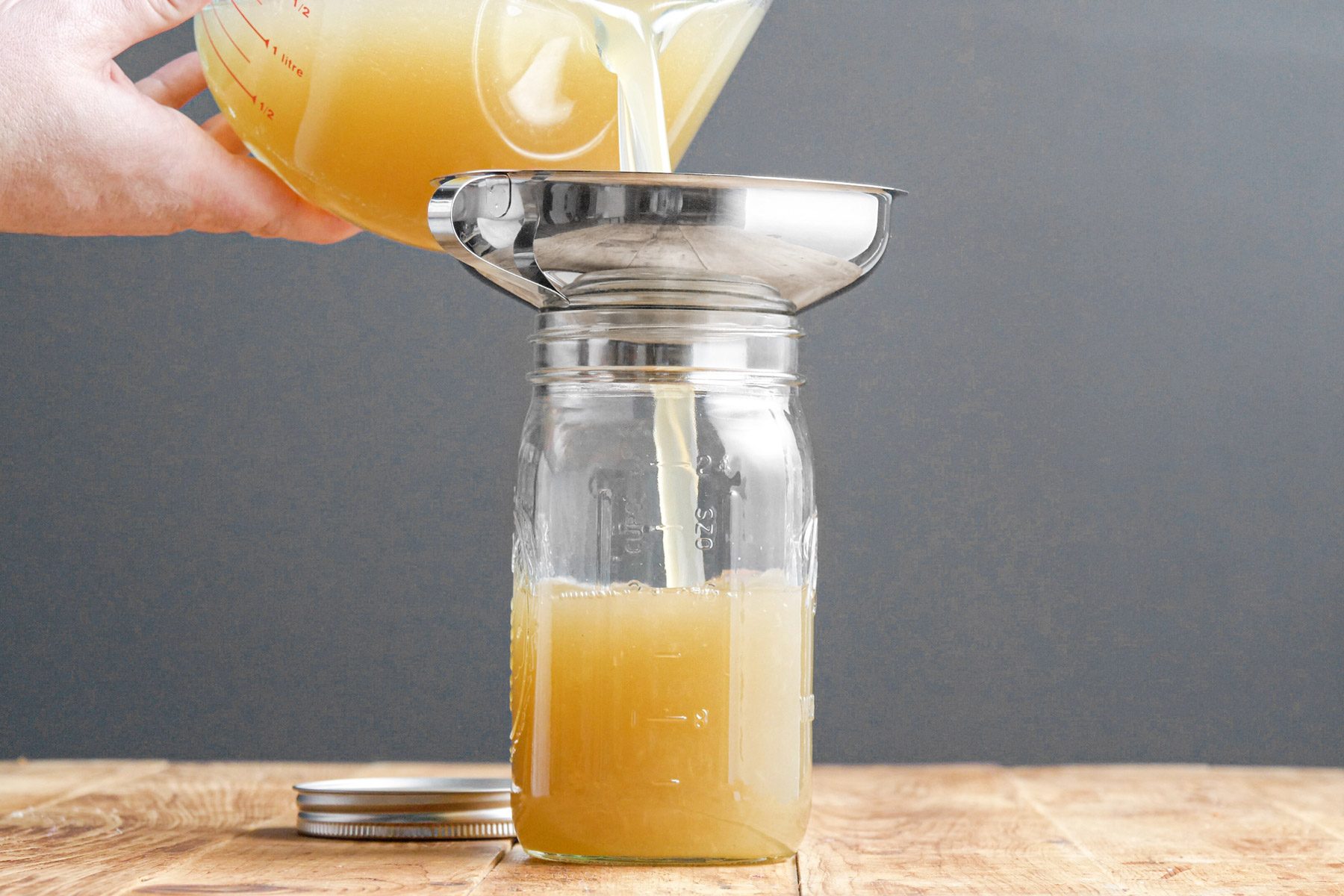 Straining chicken broth in a glass jar