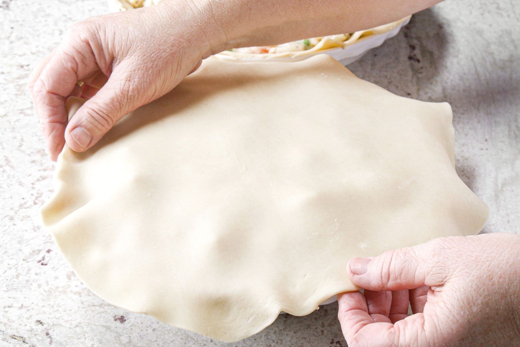Adding the top crust on the pie plate
