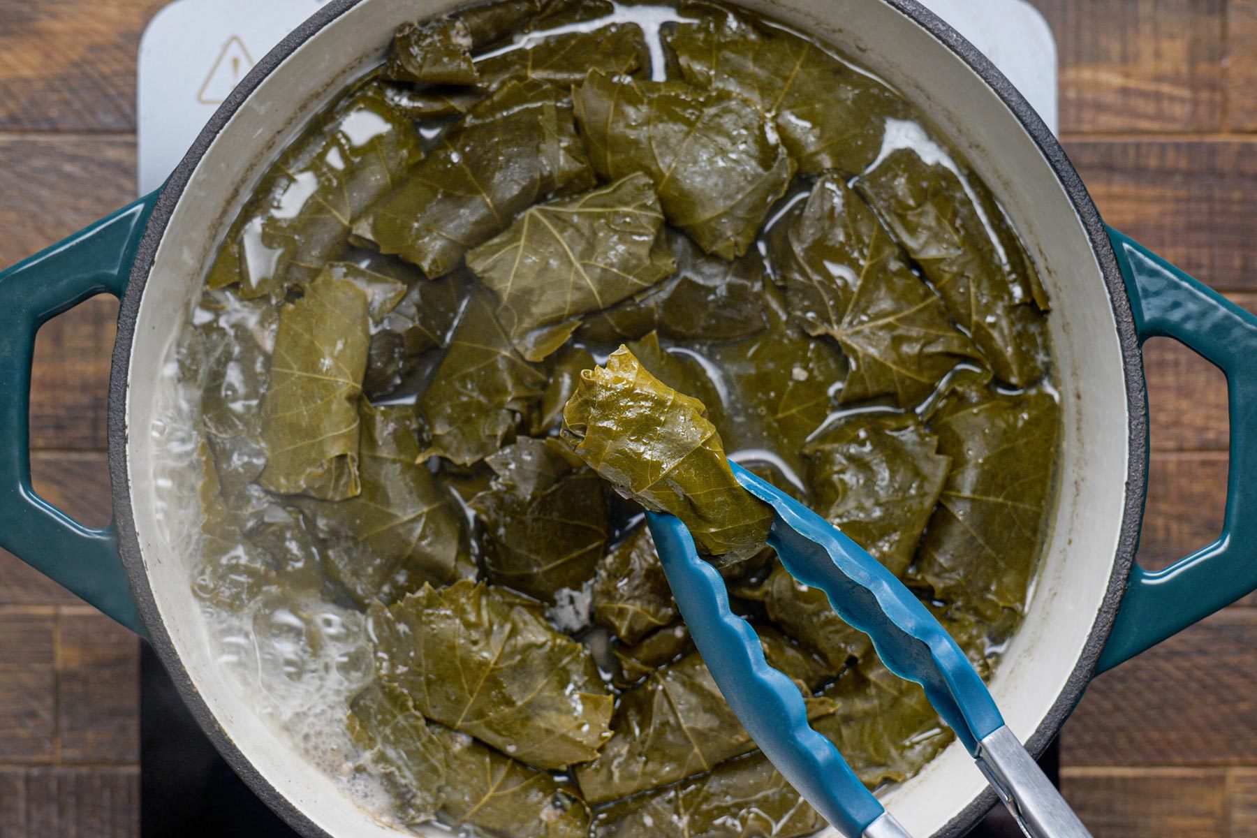 Removing the dolmades using tongs from the dutch oven
