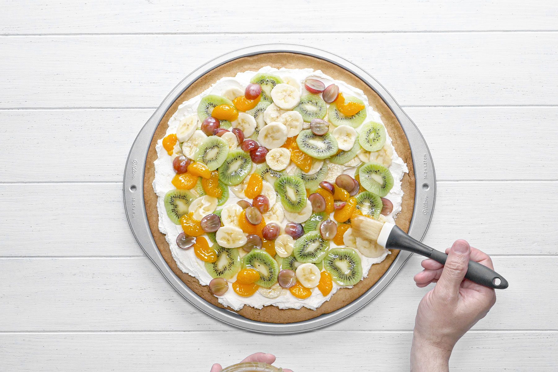 Glazing the Fruit Pizza with sugar syrup