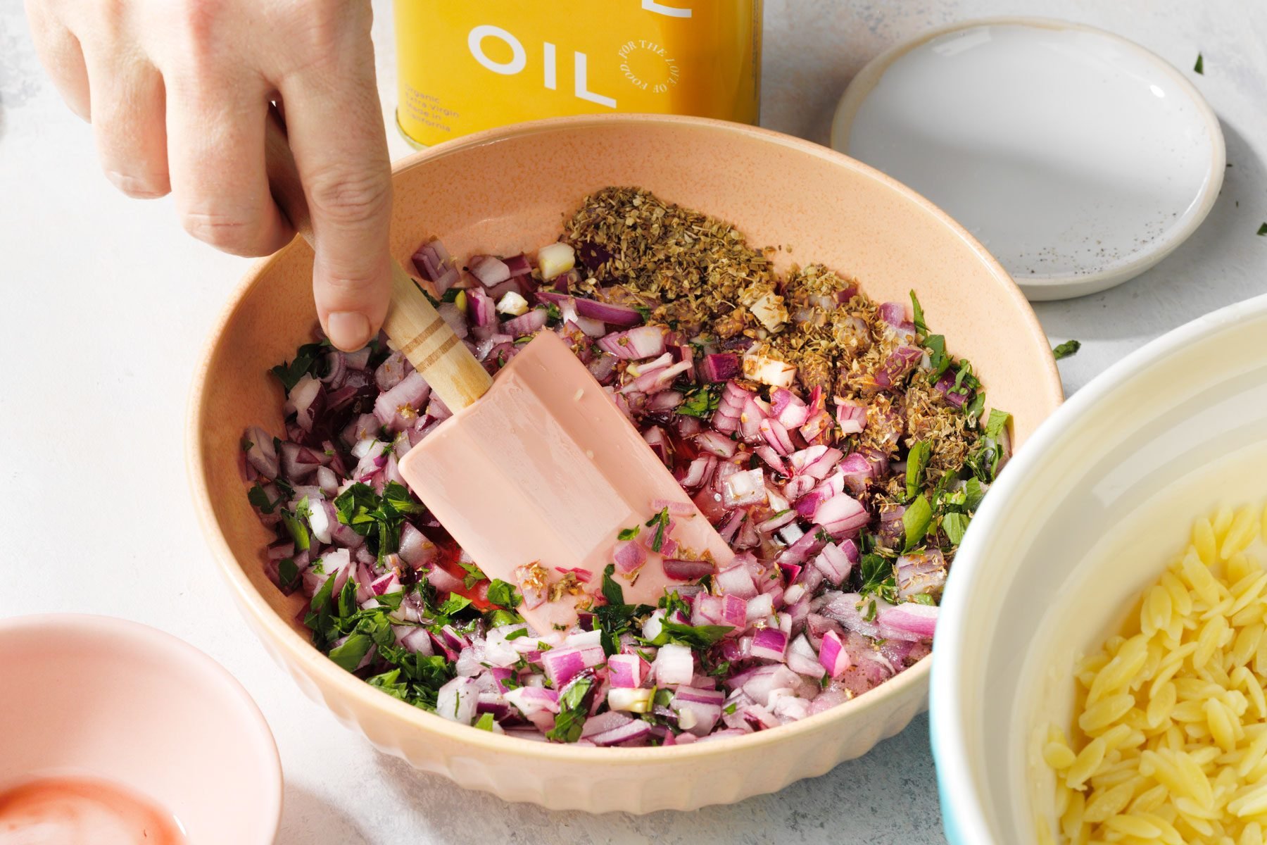 Combining the onion, parsley, vinegar, oregano in a large bowl using a spatula