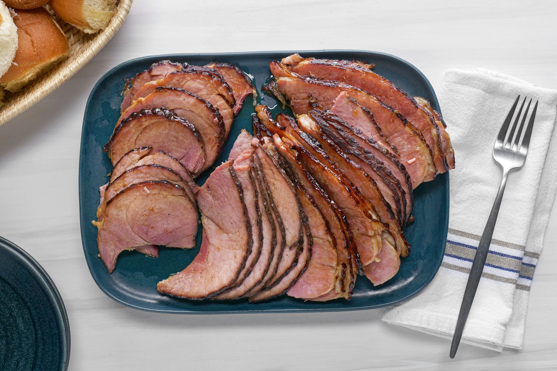 Maple Glazed Ham served in a plate with a fork on a side on a table cloth
