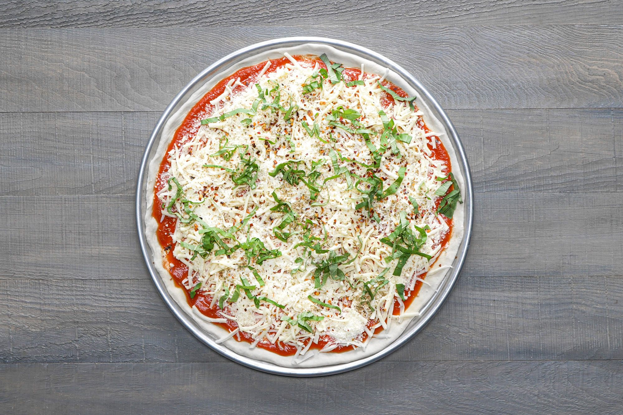 Spread the topping on the crust and top it up with mozzarella and Romano cheeses, basil, oregano and pepper flakes