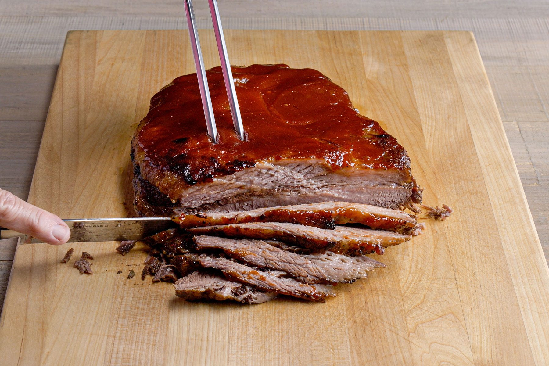 Slicing the brisket with knife over wooden board