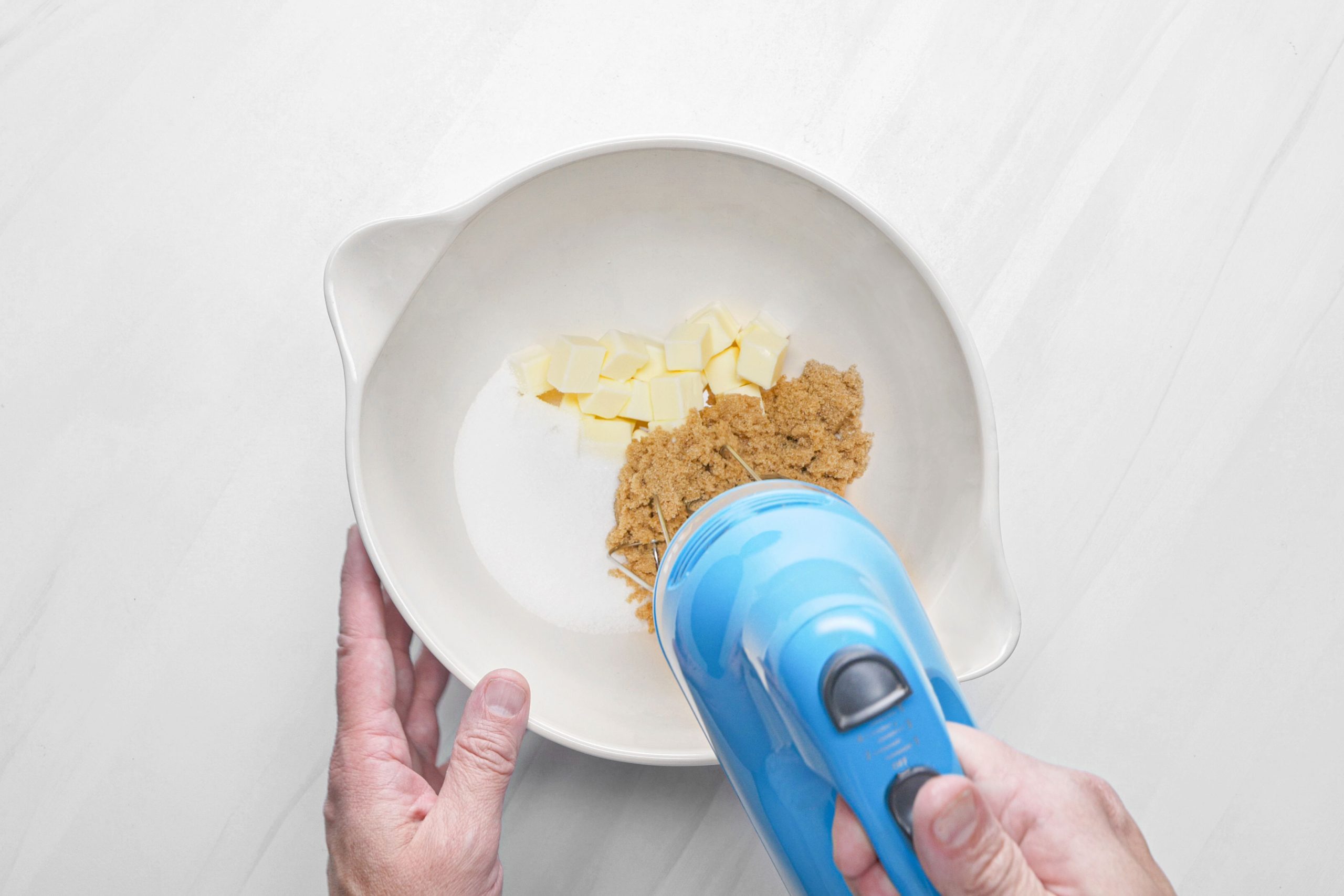 Beating the sugar and butter in a bowl with hand mixer