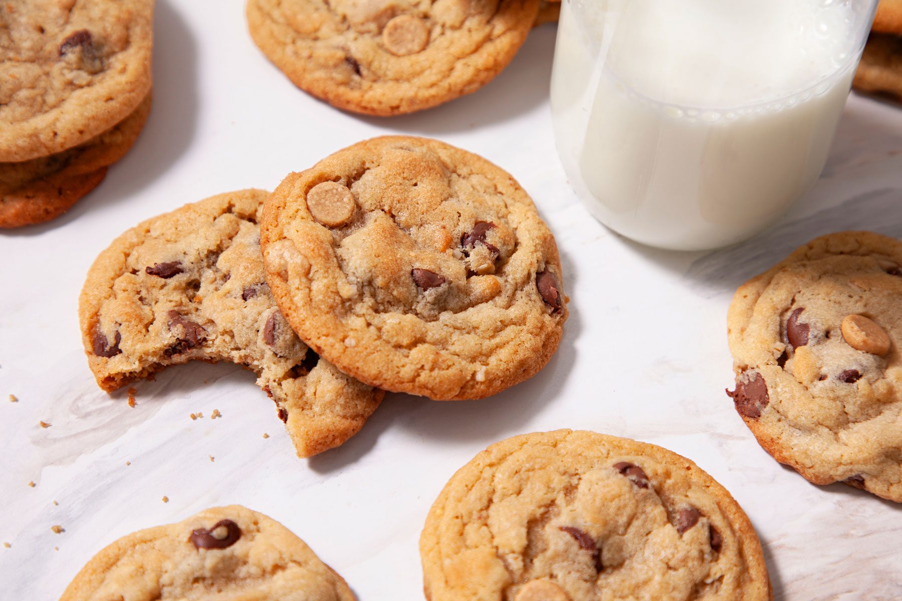 Peanut Butter Oatmeal Chip Cookies arranged on a white table with a glass of milk on side