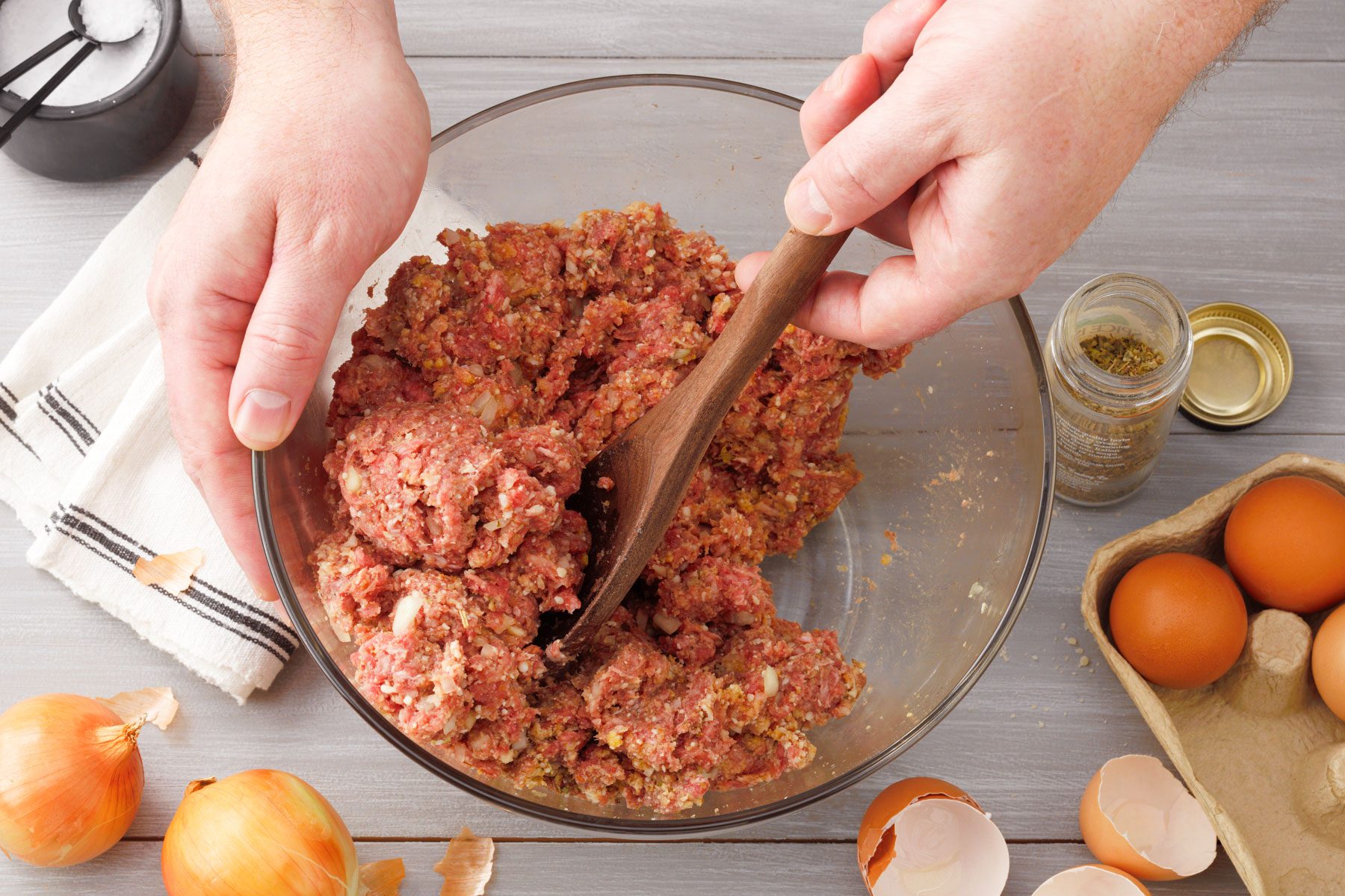 Mixing beef eggs and other ingredients in a large bowl
