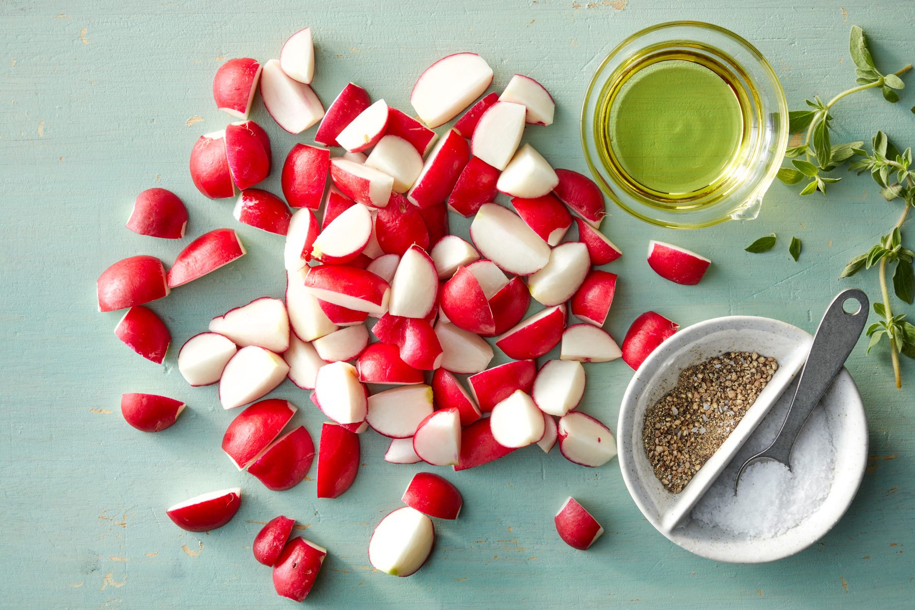 A pile of radishes and a bowl of oil