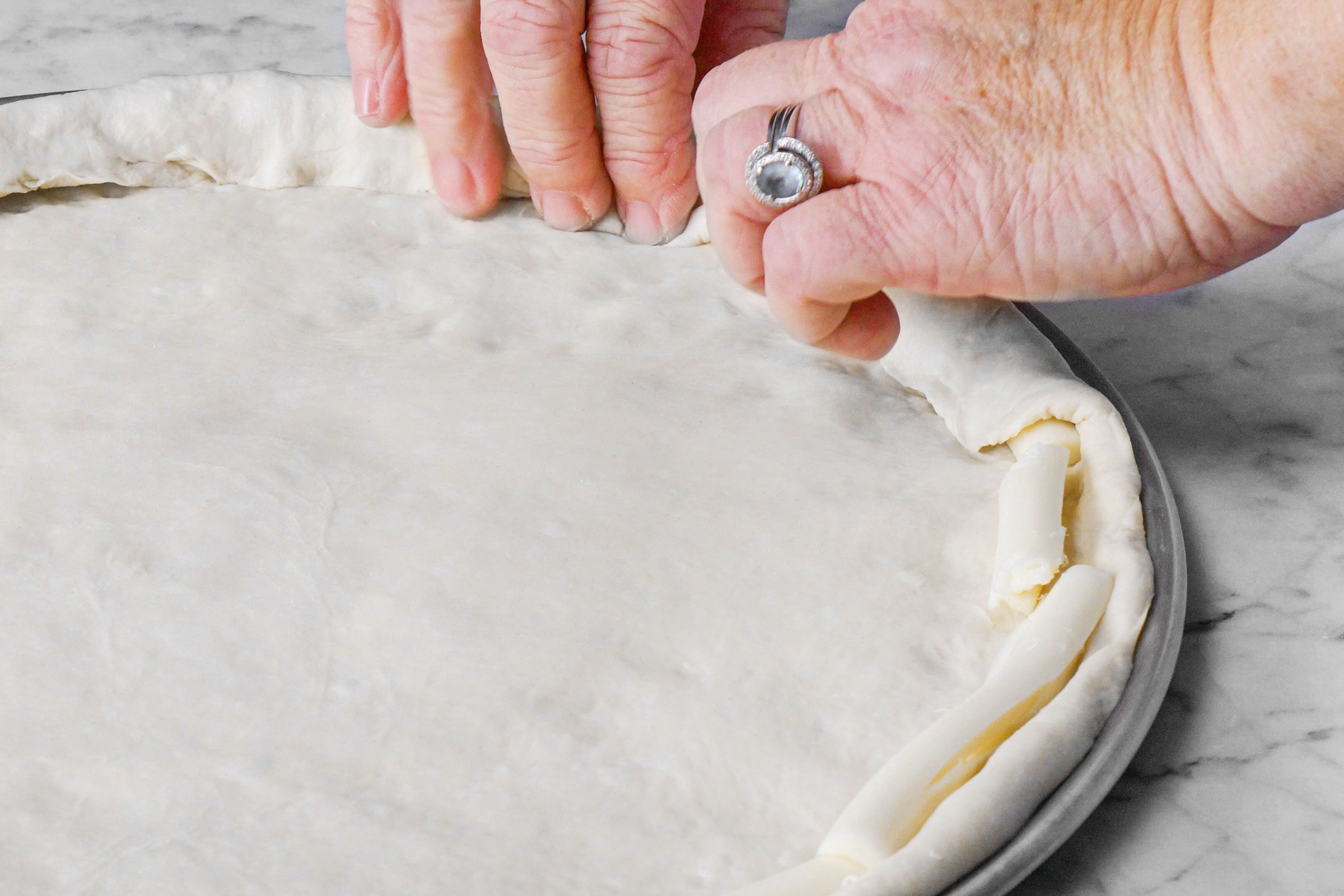 putting cheese sticks in the crust and folding the dough over the cheesesticks