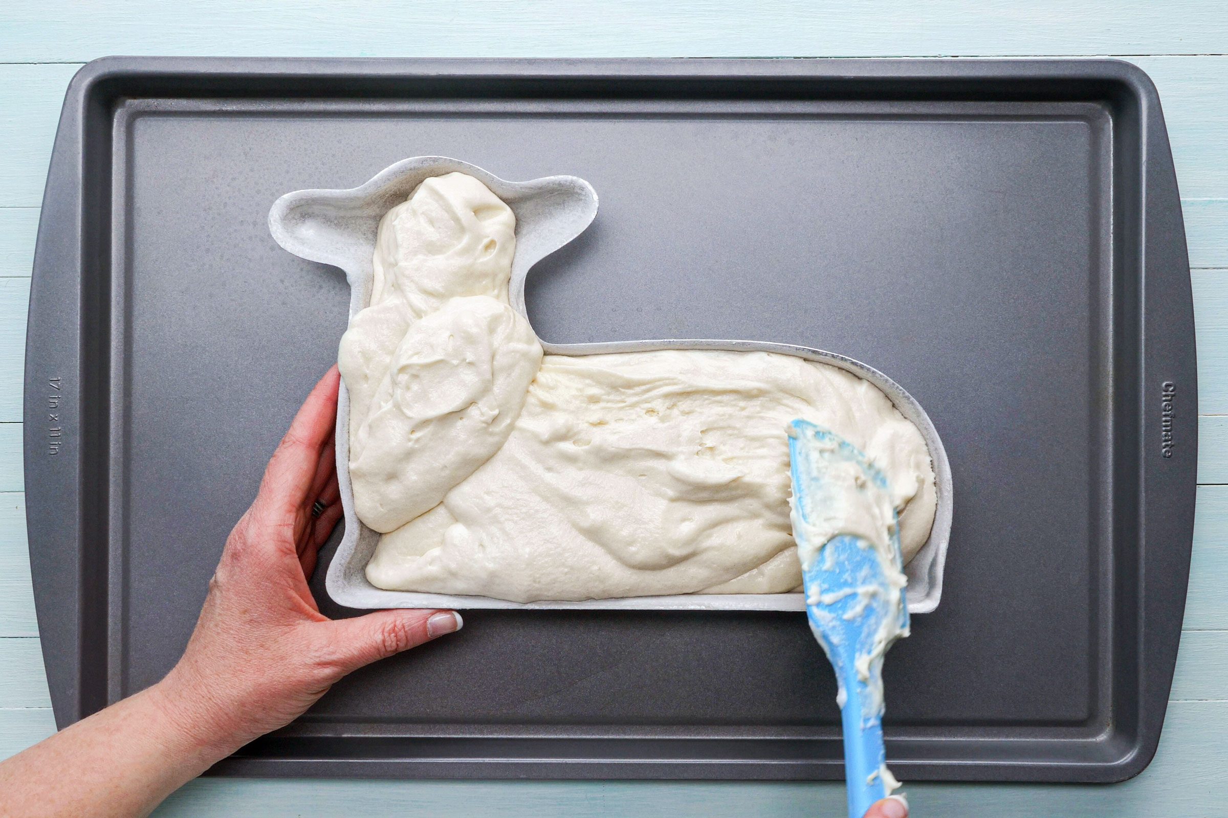 putting cake batter in cake pan shaped like a lamb