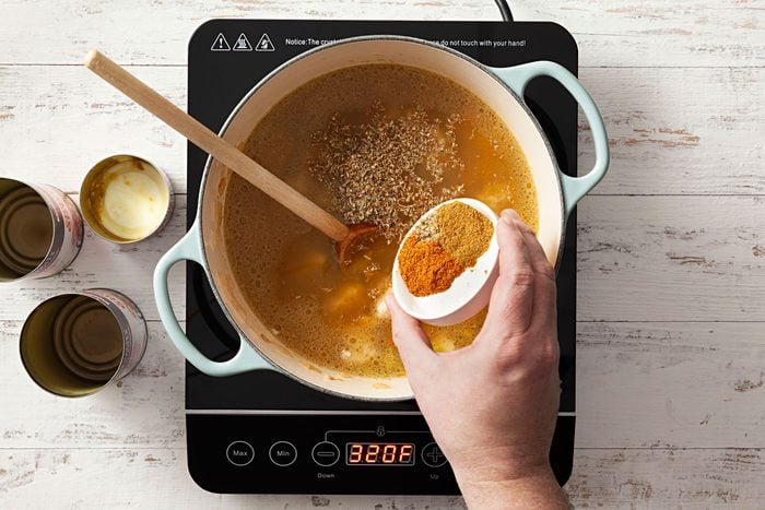 Mixing green chiles, cumin, oregano in a broth