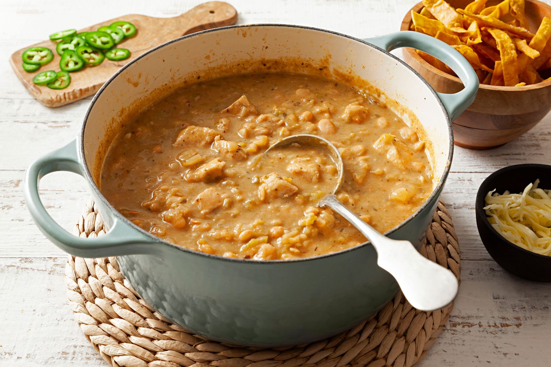 White Chicken Chili served in a large on a with chips on a wooden table