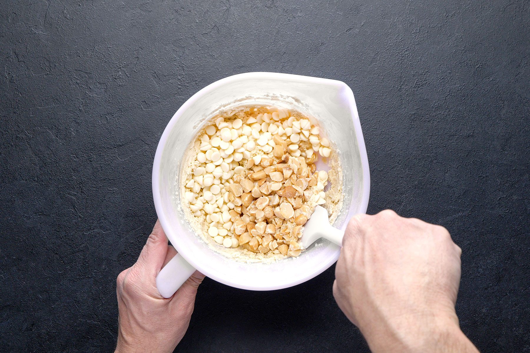 Folding Nuts and white baking chips in bowl