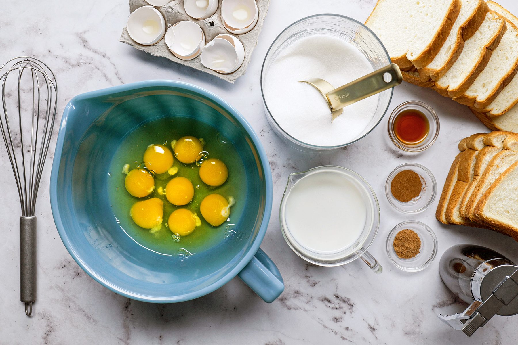 Various ingredients including eggs, milk, and bread arranged on a kitchen counter