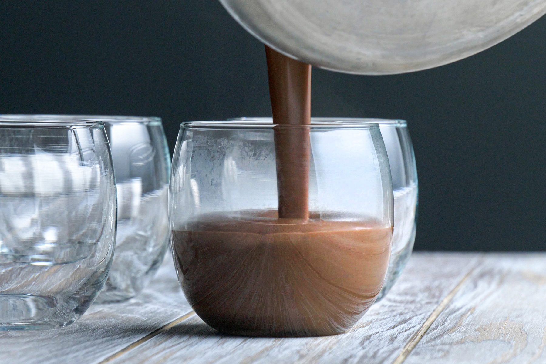 A person pouring chocolate milk into a glass