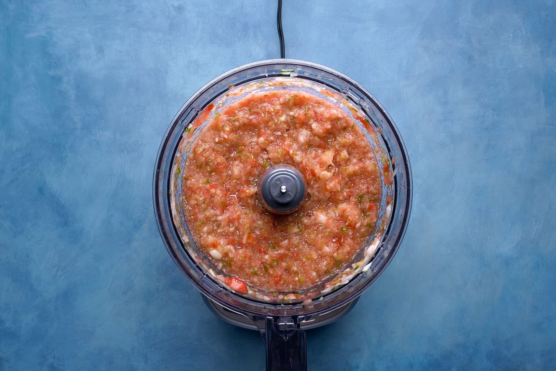 Tomato paste in a blender on a blue countertop
