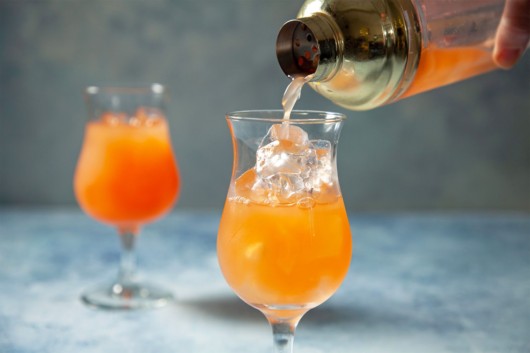 wide shot of sweet rum punch poured into cocktail glasses