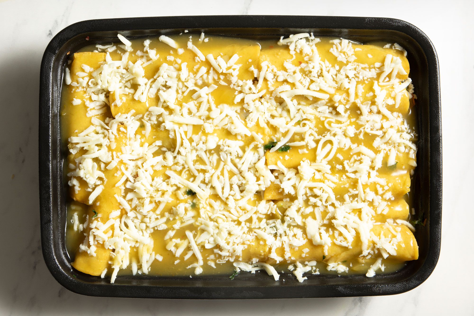 overhead shot; white background; shrimp mixture off center on each tortilla; sprinkled with shredded cheese;