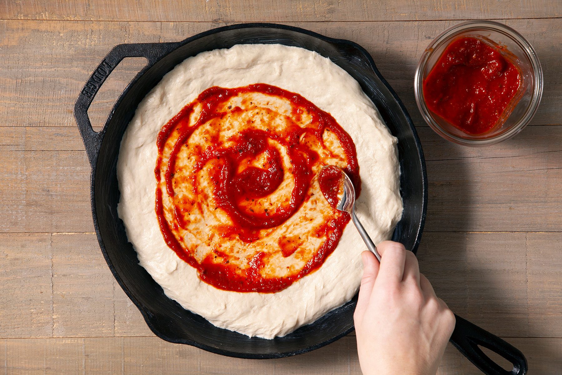 Spreading pizza sauce on dough