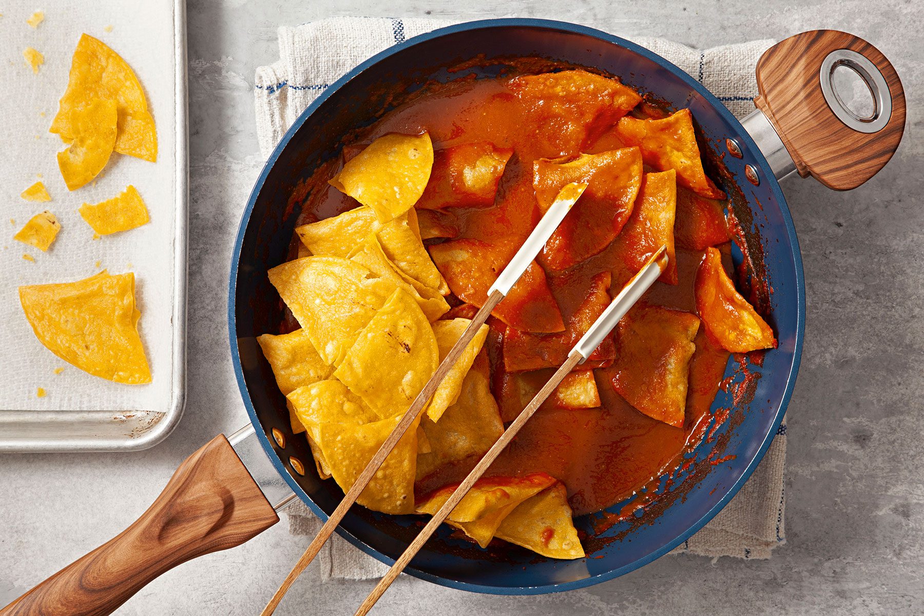 Covering the tortillas in sauce with tongs