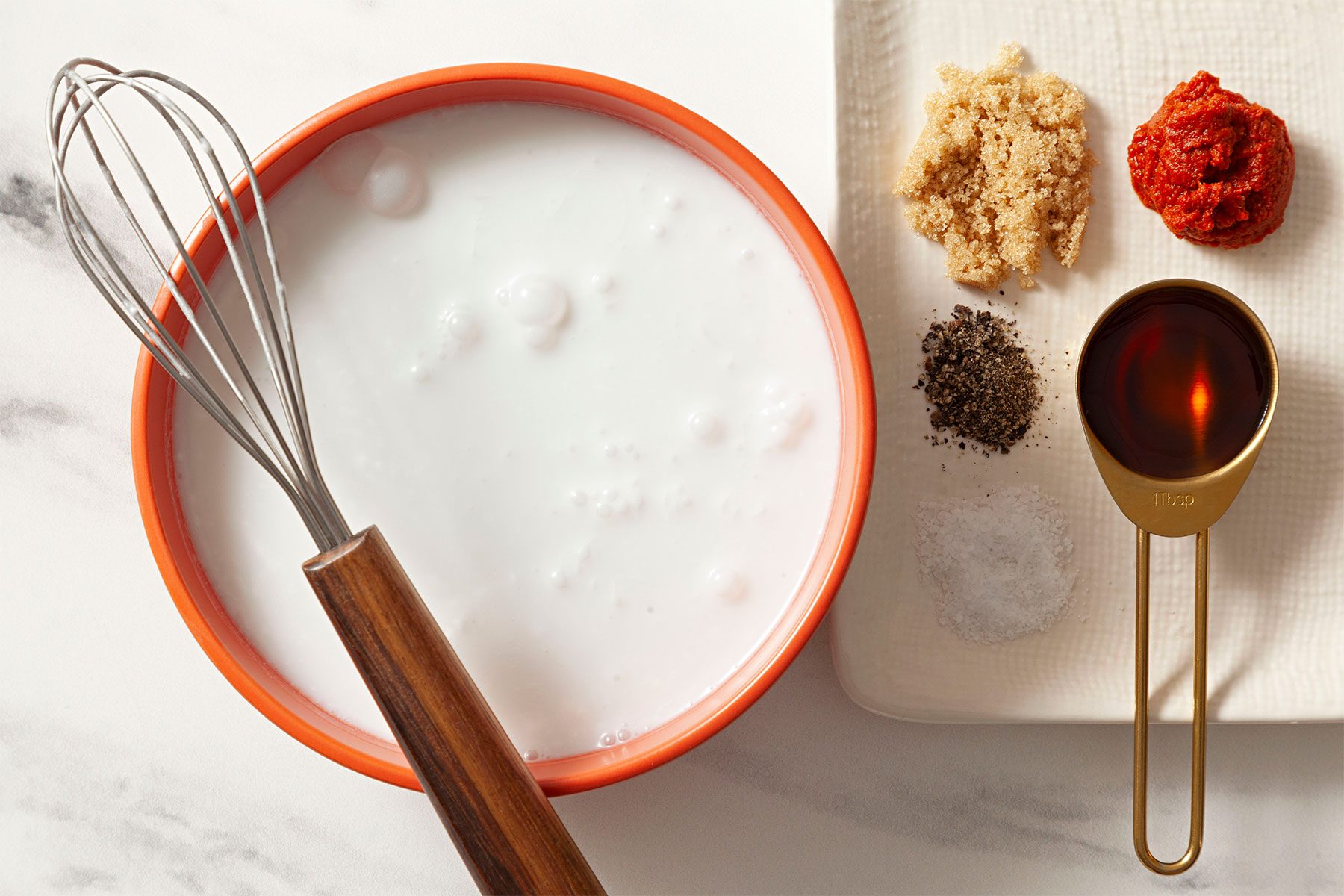 whisking tool kept on the rim of bowl full of milk 