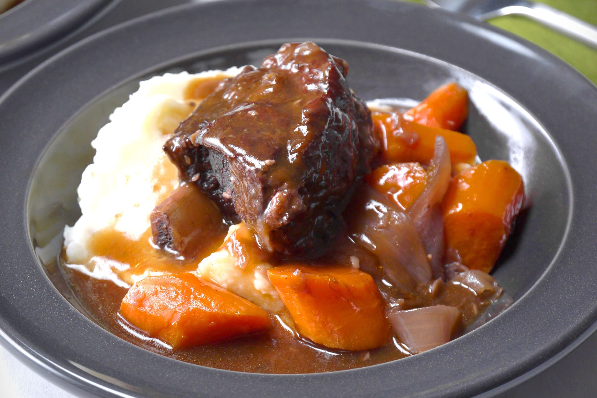 close shot of Instant Pot Short Ribs served on grey plate on white background