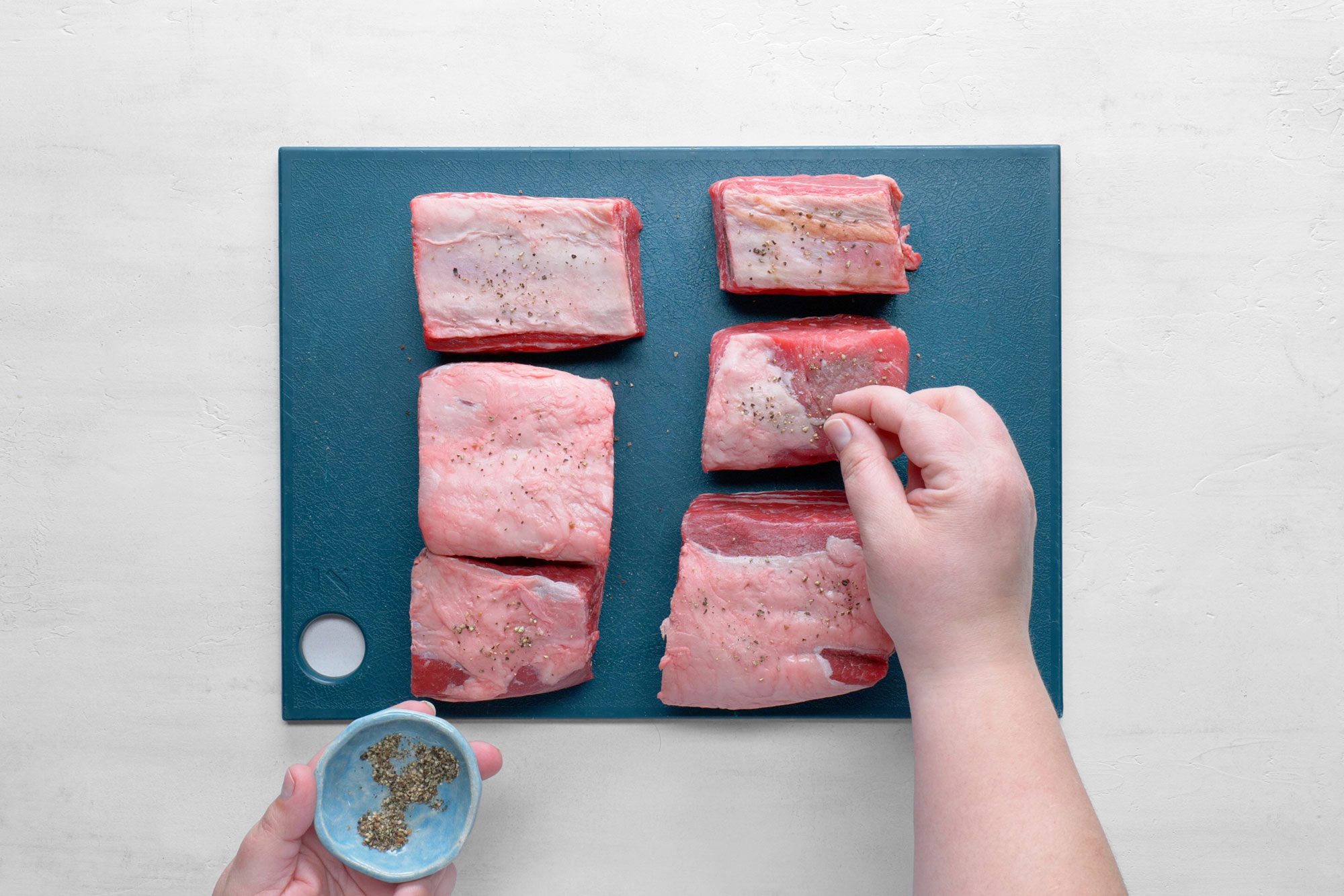 overhead shot of Sprinkle ribs with salt and pepper; white background;