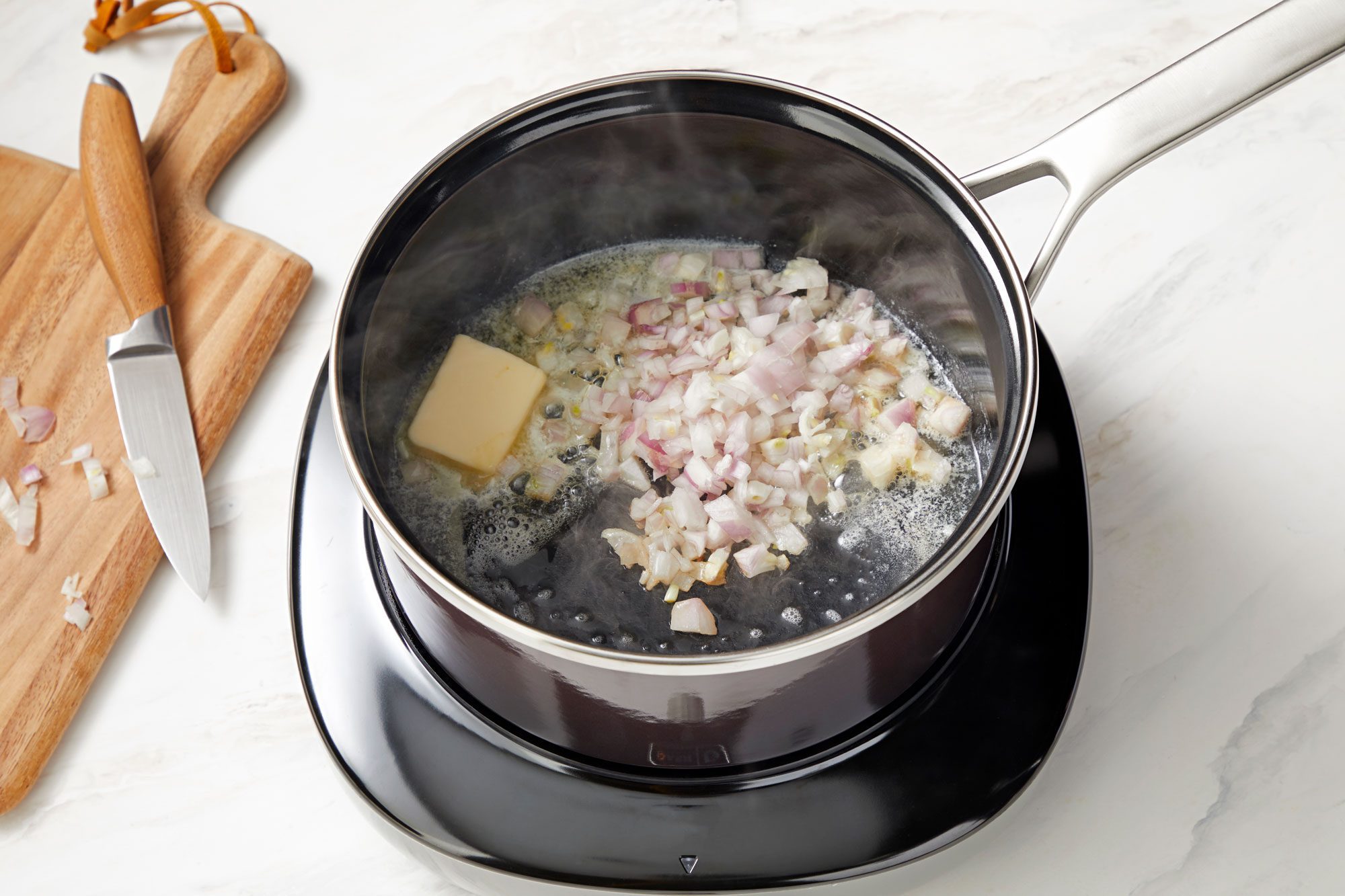 high angle shot of shallot and butter in a saucepan