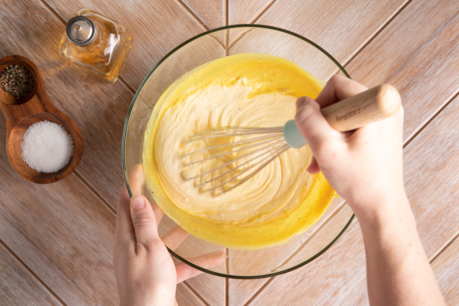 A person is whisking mixture in a glass bowl