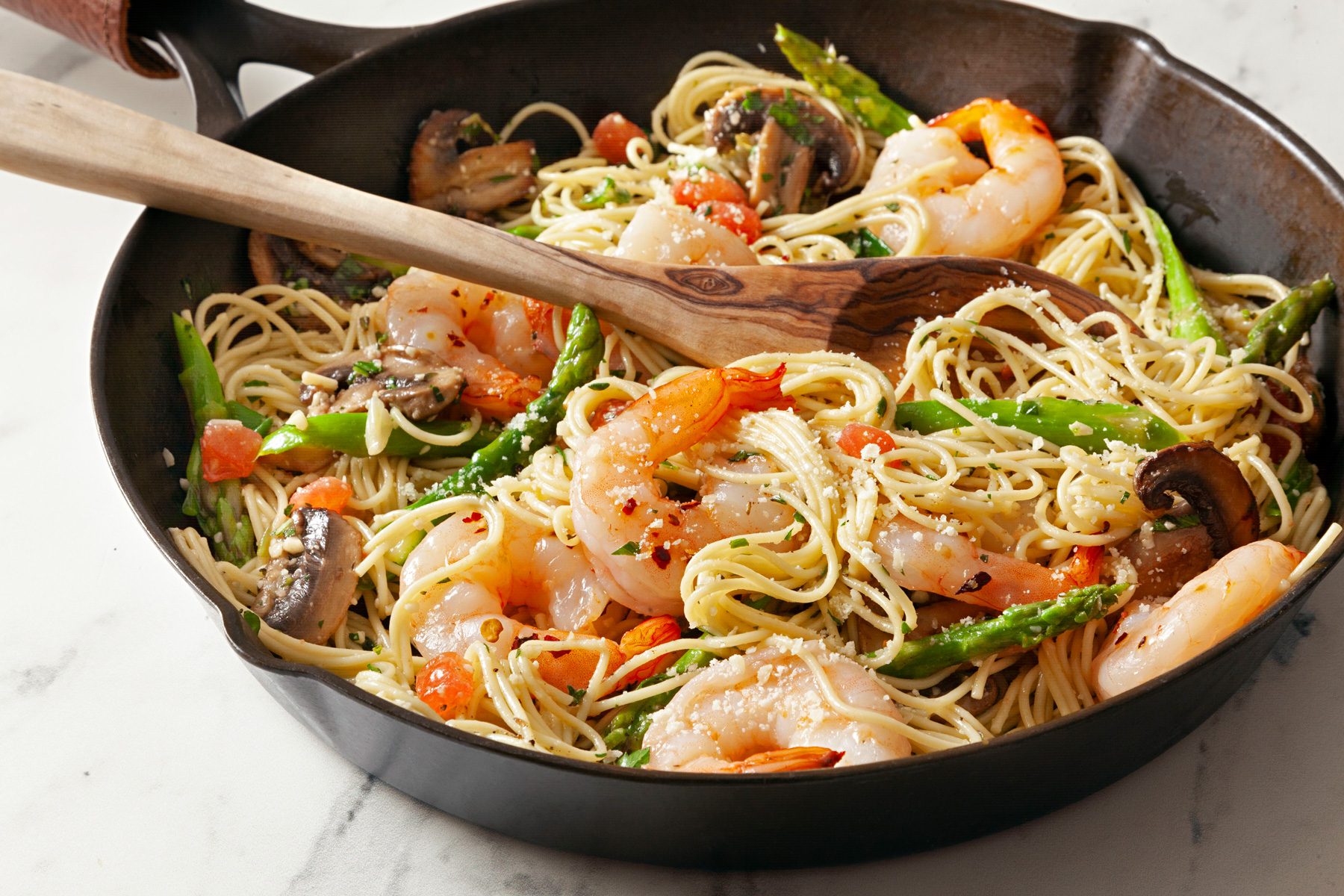 A pan of Shrimp Asparagus Pasta with a wooden spoon