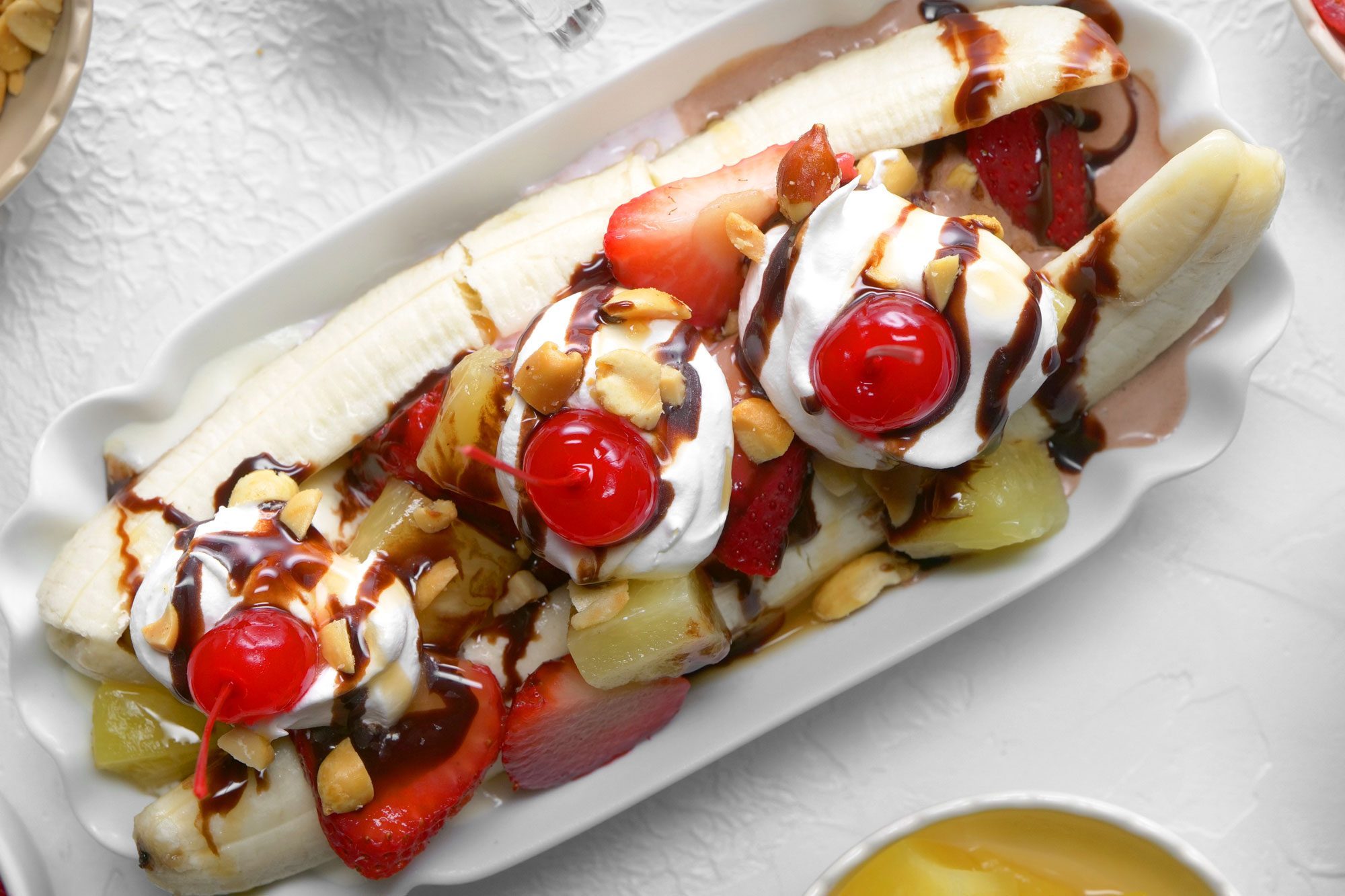 overhead shot; white background; Banana Split served on a long serving plate;