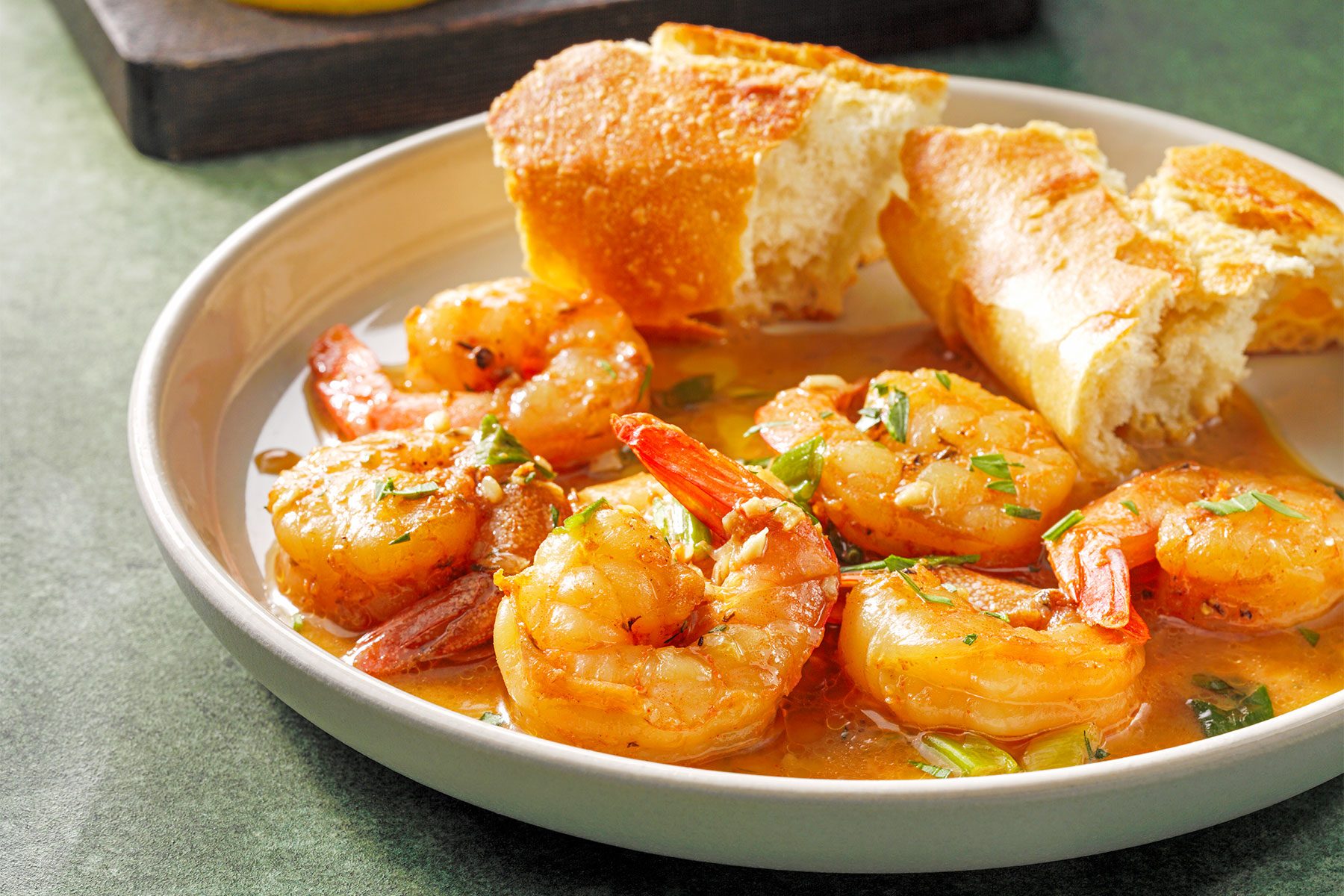 3/4 angle view shot of Barbecue Shrimp; cooked in skillet; kitchen towel; green texture background;