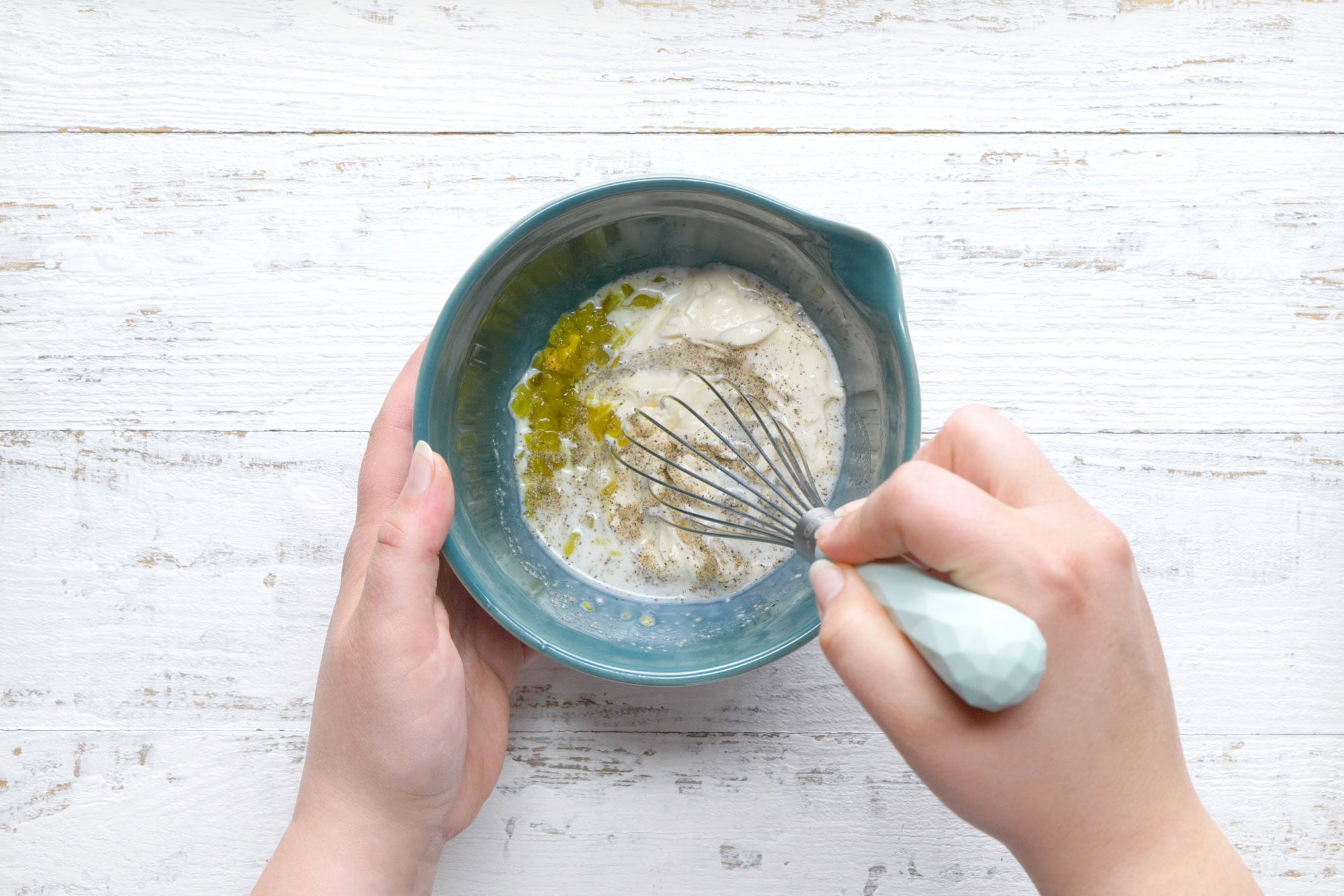 overhead shot of combine mayonnaise, milk, relish and pepper in a small bowl
