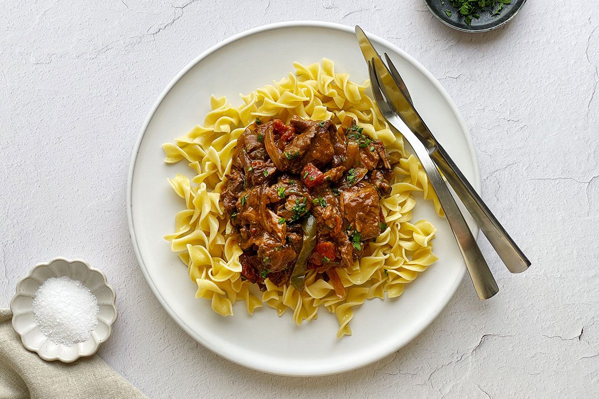 Taste of Home's Round Steak recipe on a bed of egg noodles