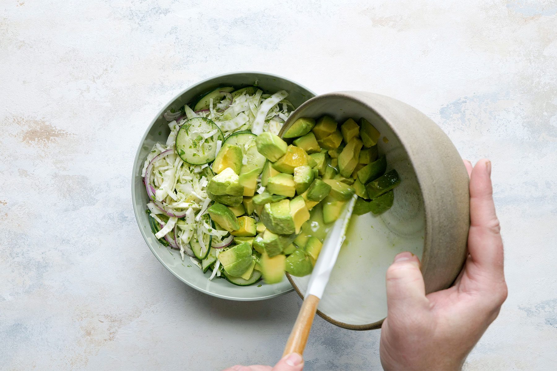 Overhead shot of adding to cabbage mixture; spatula; white marble background;