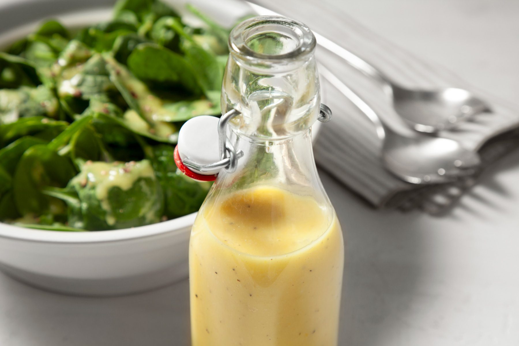 Spinach Salad Dressing in a glass bottle kept next to a bowl of salad