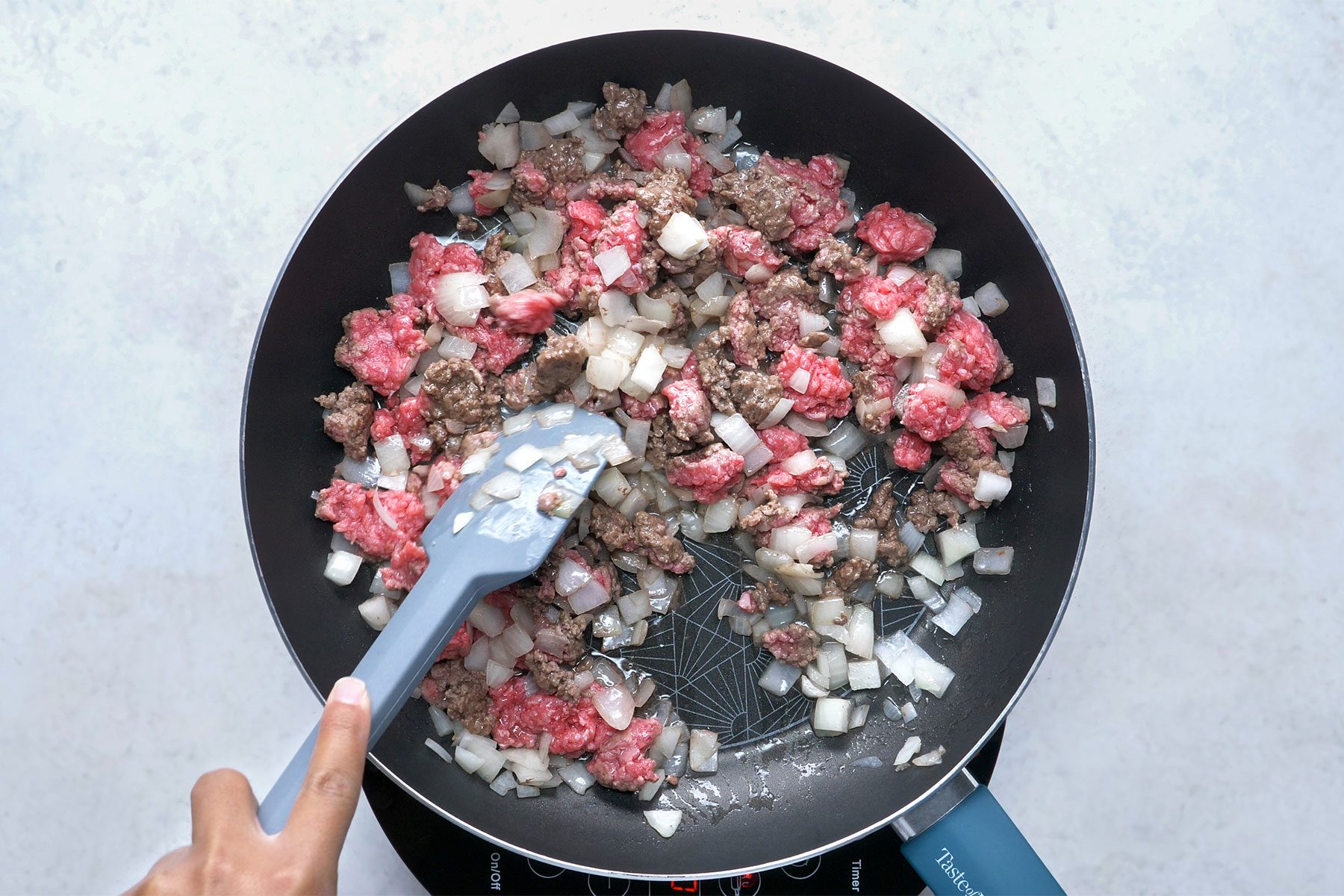 overhead shot; white background; In a large skillet, cooking beef and onion until its no longer pink;