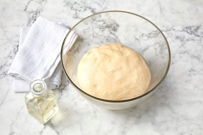 wide shot of dough in a glass bowl; marble surface;