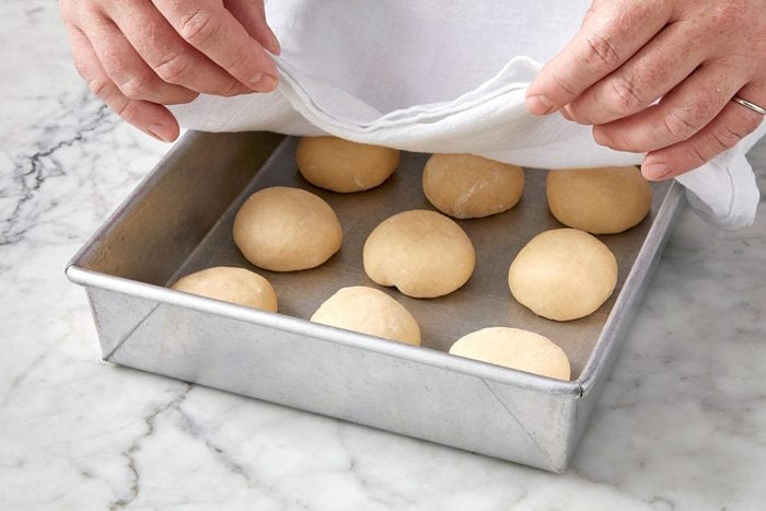 covering a baking pan with a cloth; marble surface;